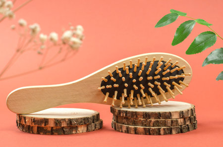 Wooden comb on a wooden podium. Hair care with natural accessories. Zero waste, no plastic