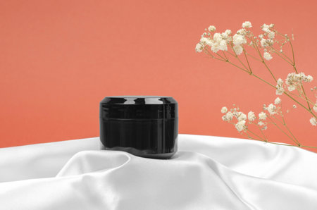 Black jar of moisturizing cream on a silk fabric podiumの写真素材