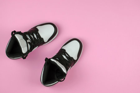Stylish new sneakers for advertising a shoe store. Black and white sneakers on a pink background, top view.の写真素材