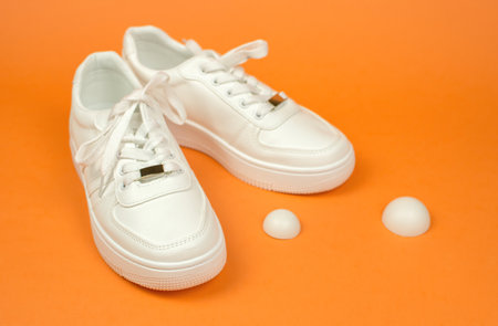 Sports shoes. Stylish white sneakers with untied laces. White sneakers on an orange background.の写真素材