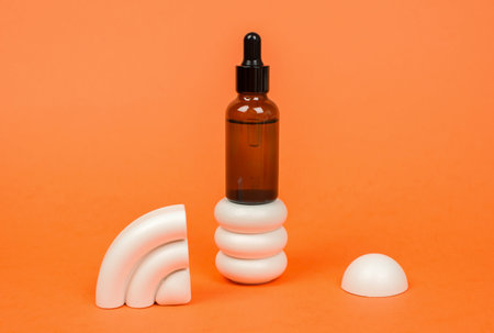 Bottle of essential oil on a round podium on a brown background. cosmetic productsの写真素材