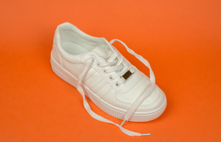Sneakers on an orange background. Stylish white sneakers for advertising a shoe storeの写真素材