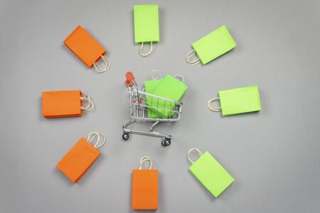 empty shopping basket with colorful shopping bags lay on grey background. shopping conceptの写真素材
