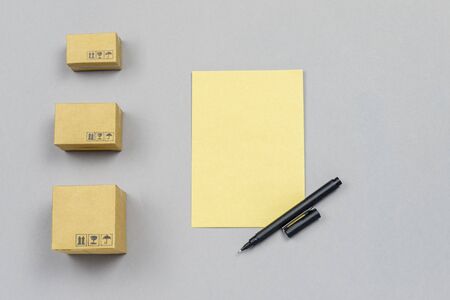 delivery concept. little boxes, sheet of paper and pen on neutral background