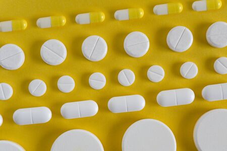 rows of pills on yellow background. medicine concept or backgroundの写真素材