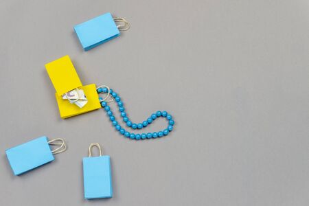 yellow and blue shopping bags with money and blue necklace on grey backgroundの写真素材