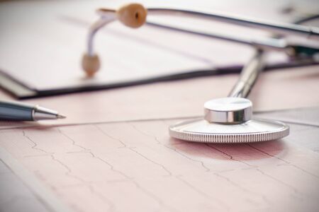 stethoscope with pen glasses, magnifier and cardiogram and other medicine equipment lay on a tableの写真素材