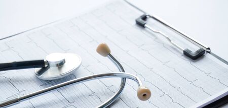 cardiogram with stethoscope, pen, magnifier, pills and glasses lay on a tableの写真素材