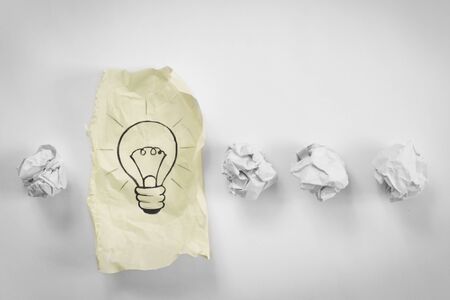 row of paper balls with sheet of paper  and bulb on itの写真素材