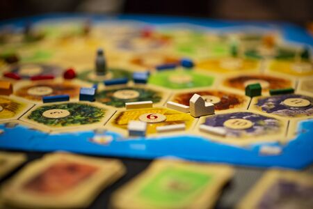 Kharkiv, Ukraine - January 05 2018: The Settlers of Catan board game, ongoing multiple player game. Settlement in focus. Bokeh of the map with game objects.のeditorial素材