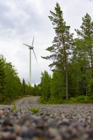 Single Wind Turbine in the middle of the green forest under blue sky with clouds. Windfarm, wind...