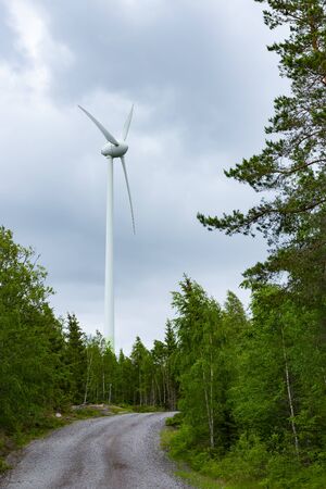 Single Wind Turbine in the middle of the green forest under blue sky with clouds. Windfarm, wind...