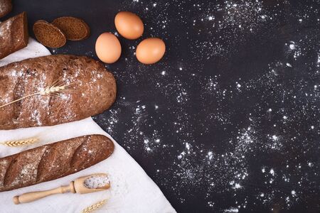 Bread border on wood with copy space background. Brown and white whole grain loaves still life composition with wheat ears scattered around. Bakery and grocery food store concept.の写真素材