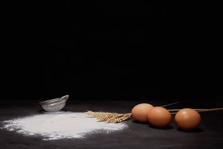 baked oval rye bread in sprinkles of white flour, black backgroundの写真素材