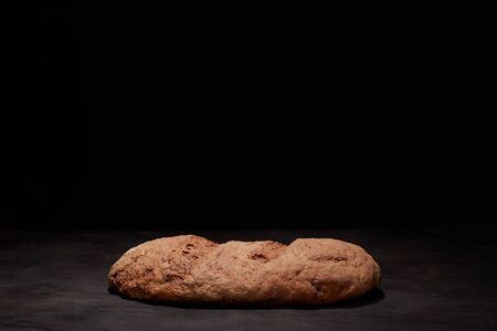 Eliptic form bread on a black background, bread from a stove on dark boards, a dough for a designer,...