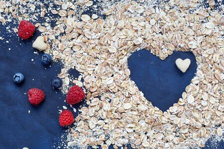 Raspberries and blueberries on blue background. Cereals.の写真素材
