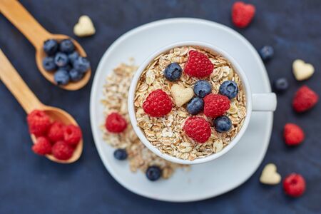 Raspberries and blueberries on blue background. Cereals.の写真素材