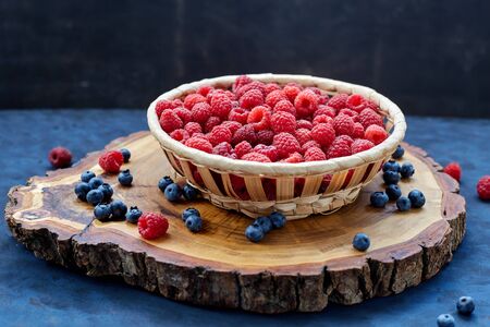 Raspberries and blueberries on blue background. Cereals.