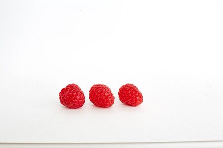 three raspberries on white background