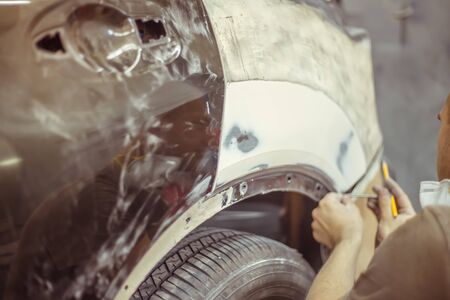 automobile repairman painter in protective workwear and painting car body in paint chamberの写真素材