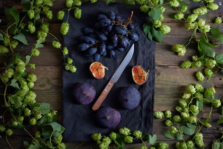 Top view of grapes with water drops, figs and hops on wooden tableの写真素材