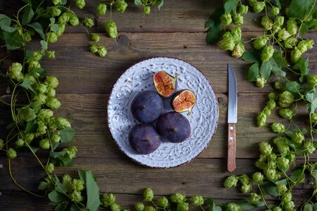Top view of grapes with water drops, figs and hops on wooden tableの写真素材