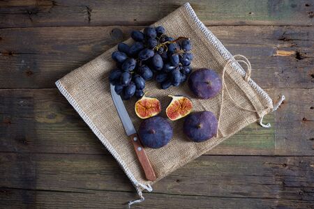 Top view of grapes with water drops, figs and hops on wooden tableの写真素材