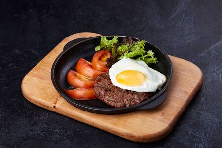 Pan winth fried egg, sliced tomatoes, salad and cutletの写真素材