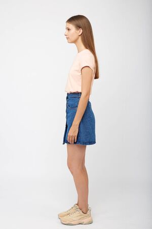 Teenager girl in a denim blue skirt on a white background.の写真素材