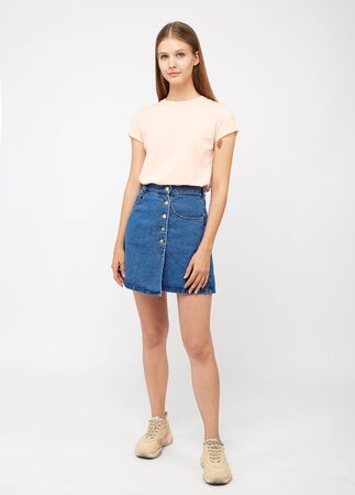 Teenager girl in a denim blue skirt on a white background.の写真素材