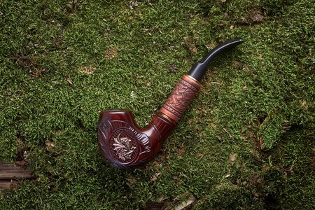 Tobacco pipe on old orange wooden background.
