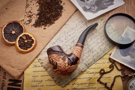 Tobacco pipe on old wooden background. Vintage letters, watches, coins and tobacco, slices of dried grapefruit.の写真素材
