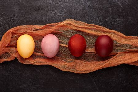 Easter composition with colored eggs on vintage textile, top view, flat lay. Naturally colored...
