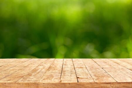 Empty wooden deck table with foliage bokeh background. Ready for product display montage.