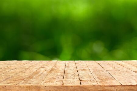 Empty wooden deck table with foliage bokeh background. Ready for product display montage.