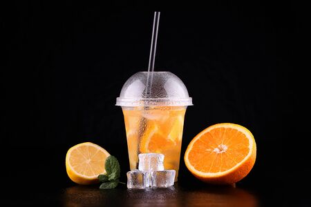 Lemonade to go cup with mint, orange and lemon on black background, isolatedの写真素材