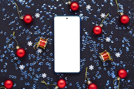 Mobile phone with empty screen on black table. Christmas decoration.の写真素材