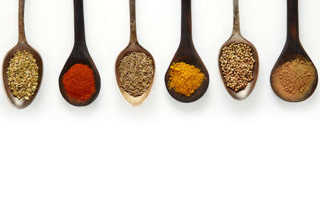 Spoons filled with various spices on white background