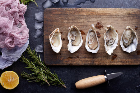 Fresh opened oysters, ice and lemon on a round plate, stone textured background.