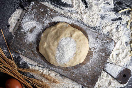 Homemade raw noodles made from flour, egg on wooden bowl on black. Top viewの写真素材
