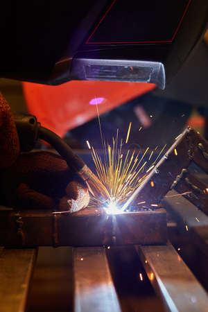 A man in a protective mask carries out welding work in the garage.
