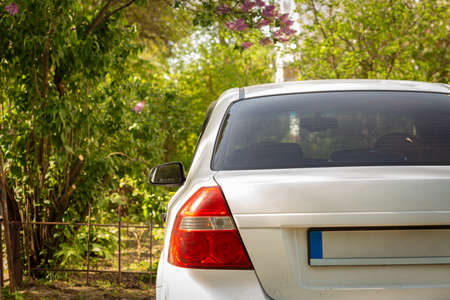 Back window of white car parked on the street in summer sunny day, rear view. Mock-up for sticker or...
