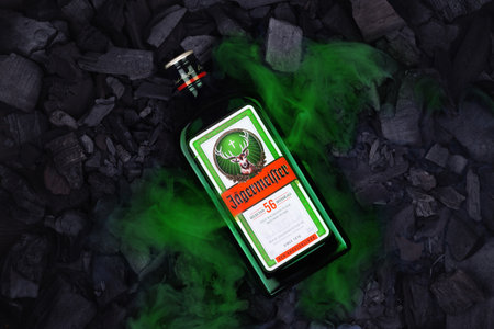 Ukraine, Poltava - July 11, 2022: Bottle of Jagermeister, German digestif made with 56 herbs and spices. bottle in coals.のeditorial素材