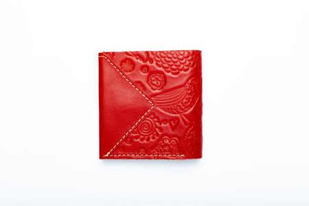 Small red leather wallet on a button on a white background, birds print. top viewの写真素材
