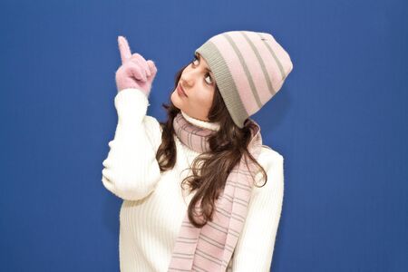 Cute dressed girl looking and pointing upward on blue backgroundの写真素材