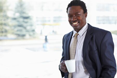 African American business man with cup at the windowの写真素材