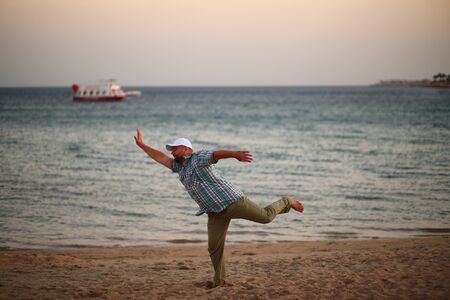 Portrait of a running caucasian man in a hurry on a sunset beach