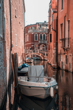 Narrow canal with small boats between brick wallsの写真素材
