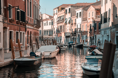 Quiet canal with moored boats and colorful housesの写真素材