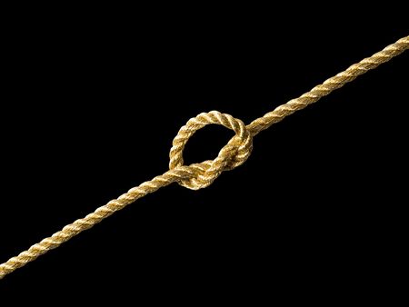 Knot on golden rope on black background (isolated).の写真素材